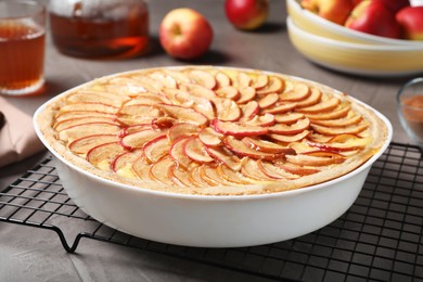 Tasty apple pie in baking dish on grey table