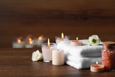 Photo of Beautiful spa composition with burning candles and flowers on wooden table. Space for text