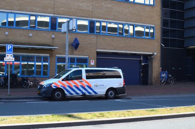 Photo of Hague, Netherlands - May 2, 2022: Police car near modern building in city