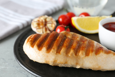 Photo of Delicious grilled chicken with vegetables and sauce on marble table, closeup