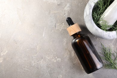 Photo of Bottle of essential oil and fresh dill on light gray textured table, flat lay. Space for text