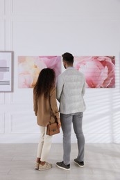 Photo of Couple at exhibition in art gallery, back view