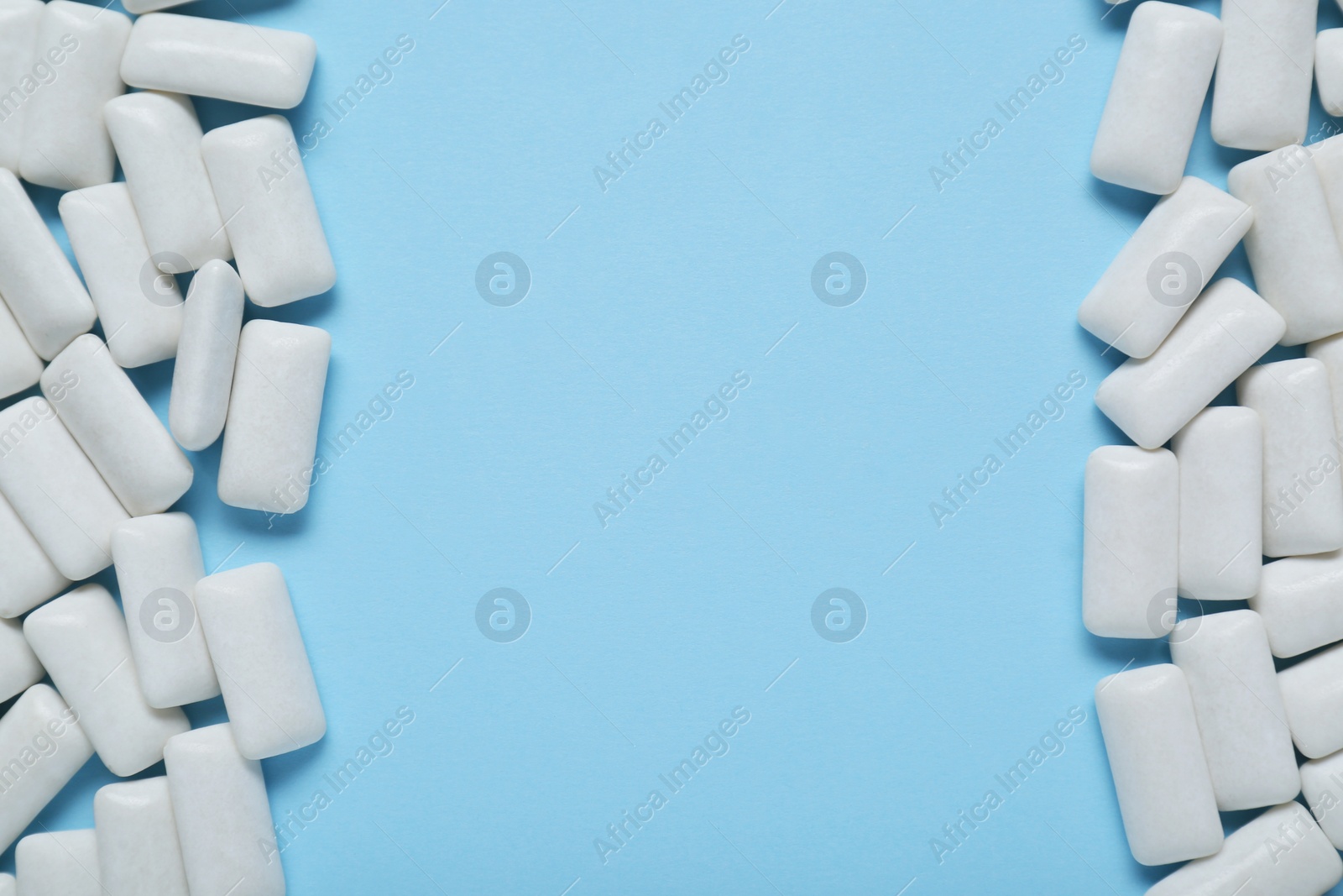 Photo of Tasty white chewing gums on light blue background, flat lay. Space for text