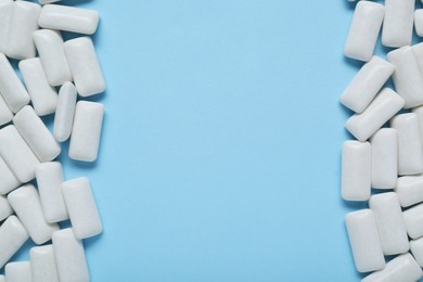 Photo of Tasty white chewing gums on light blue background, flat lay. Space for text