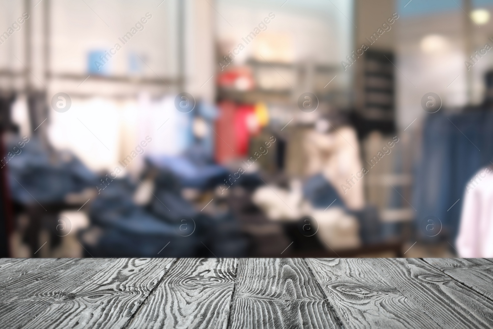 Image of Empty wooden table and blurred view of store with modern clothes