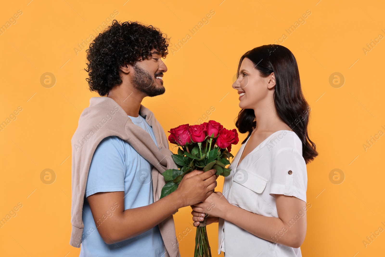 Photo of International dating. Happy couple with bouquet of roses on yellow background