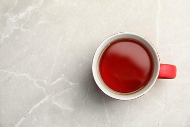 Ceramic cup of black tea on gray table, top view