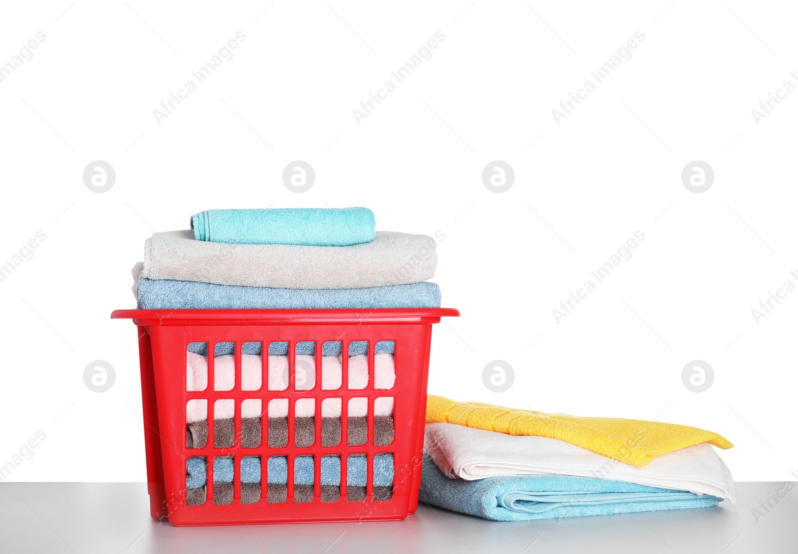 Photo of Basket with clean laundry on grey table, white background