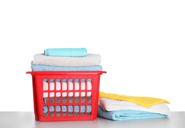 Photo of Basket with clean laundry on grey table, white background