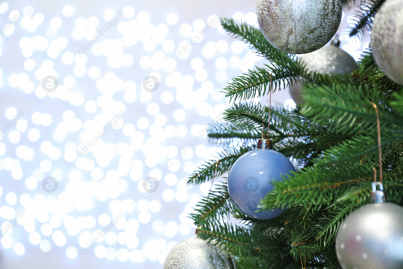 Photo of Christmas tree with festive decor against blurred fairy lights