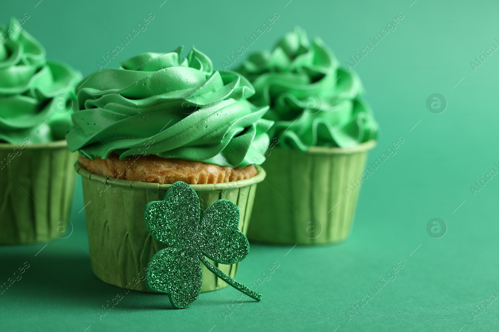 Photo of St. Patrick's day party. Tasty cupcakes on green background, closeup. Space for text