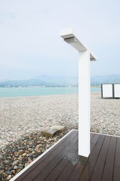 Modern outdoor shower with wooden platform on seashore