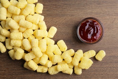 Photo of Bowl of jam and delicious crispy corn sticks on wooden table, flat lay