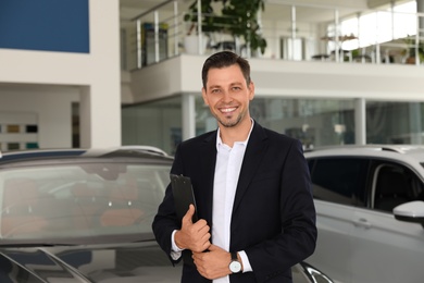 Salesman with clipboard in modern car salon