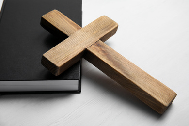 Christian cross and Bible on white wooden background, closeup. Religion concept