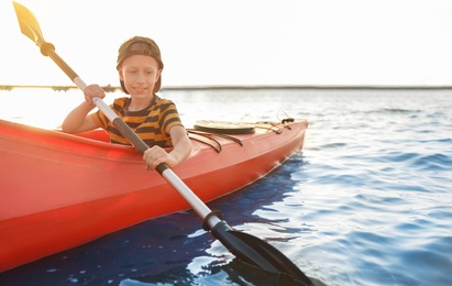 Photo of Happy little boy kayaking on river. Summer camp activity