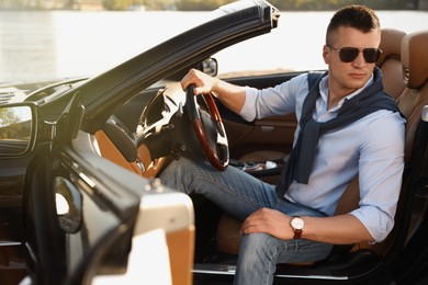 Photo of Handsome young man in luxury convertible car outdoors