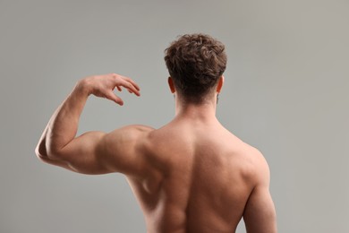 Man with muscular body on light grey background, back view