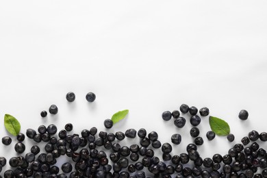 Photo of Ripe bilberries and leaves on white background, flat lay. Space for text