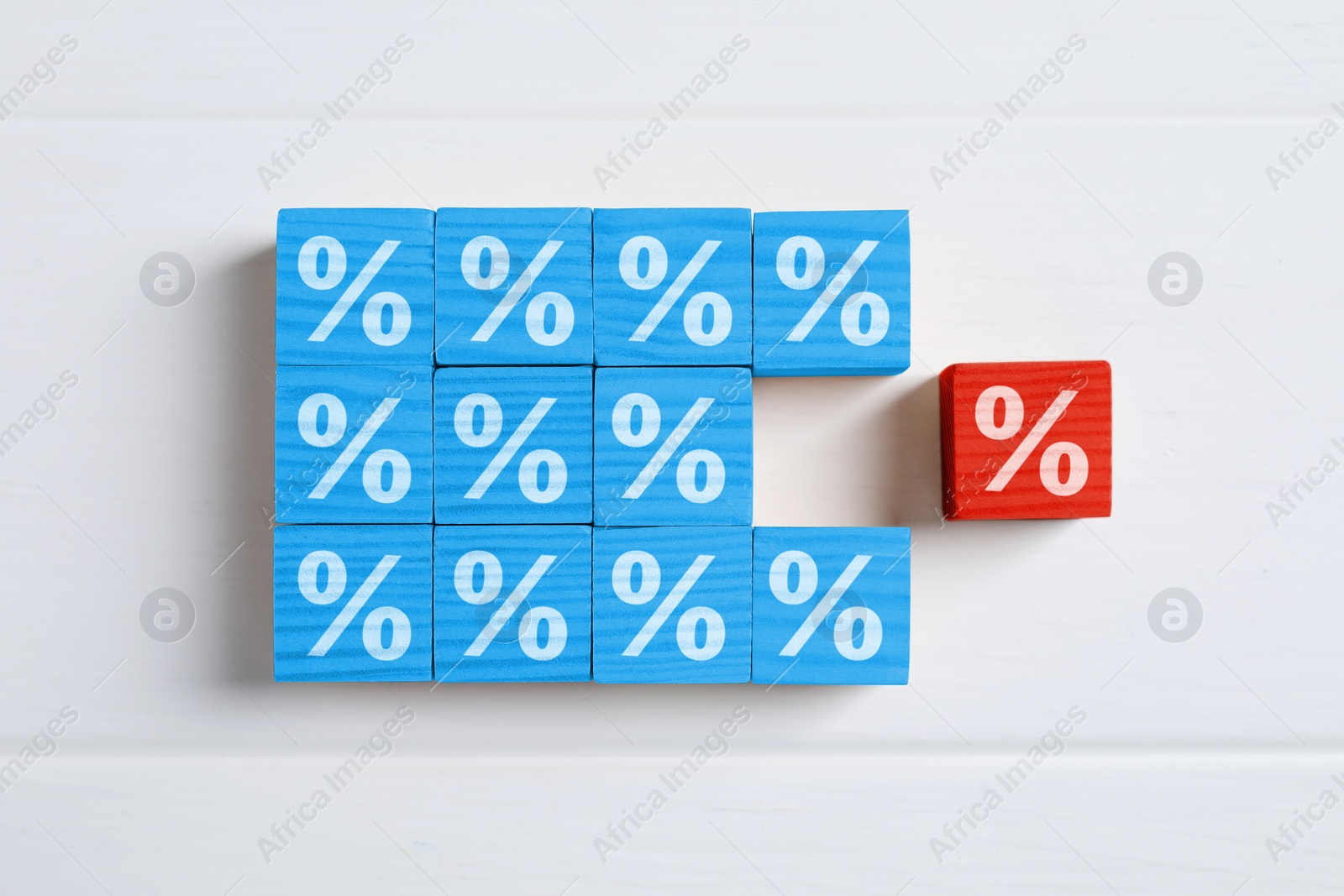 Image of Best mortgage interest rate. Red cube with percent sign among light blue ones on white wooden table, flat lay