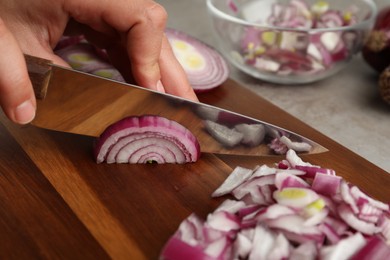 Photo of Woman cutting red onion on wooden board, closeup