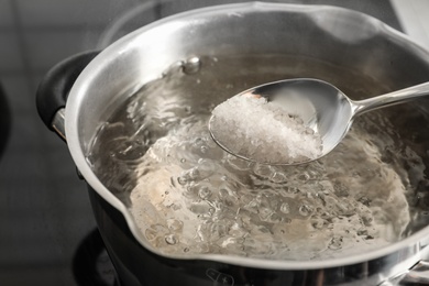 Photo of Salting boiling water in pot on stove, closeup