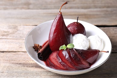 Tasty red wine poached pears and ice cream in bowl on wooden table, closeup