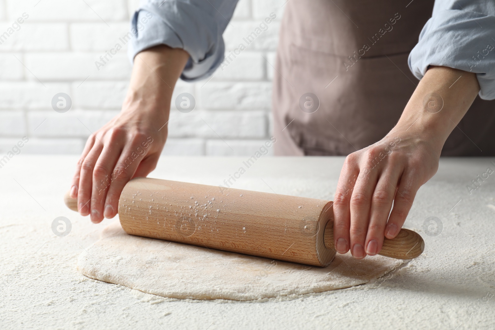 Photo of Woman rolling raw dough at table, closeup