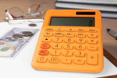 Photo of Orange calculator and money on table, closeup. Retirement concept