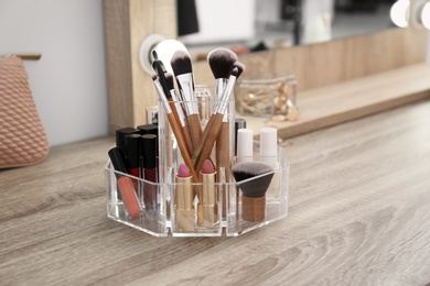 Photo of Organizer with cosmetic products for makeup on table near mirror