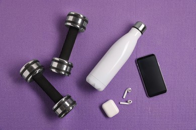 Flat lay composition with stylish thermo bottle and dumbbells on purple textured background