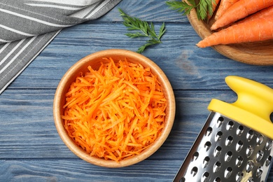 Photo of Flat lay composition with bowl of grated carrot on wooden table