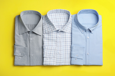 Photo of Stylish male shirts on yellow background, flat lay