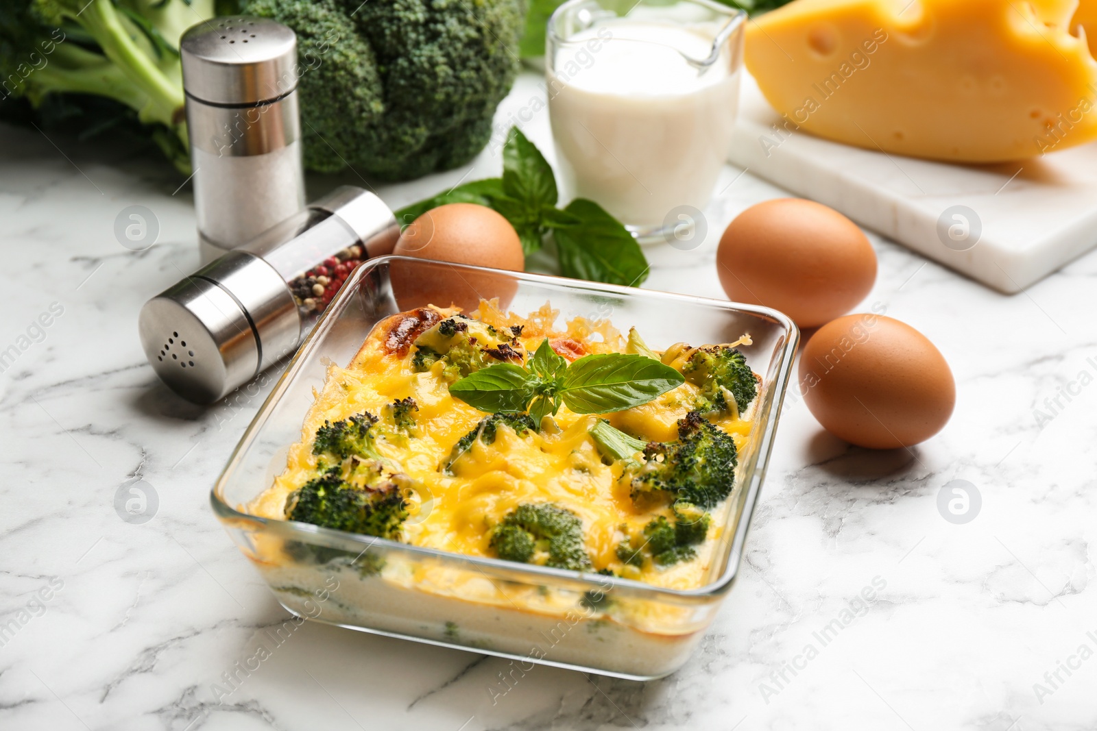 Photo of Tasty broccoli casserole in baking dish on white marble table