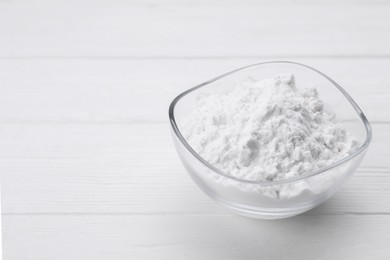 Starch in bowl on white wooden table, closeup. Space for text