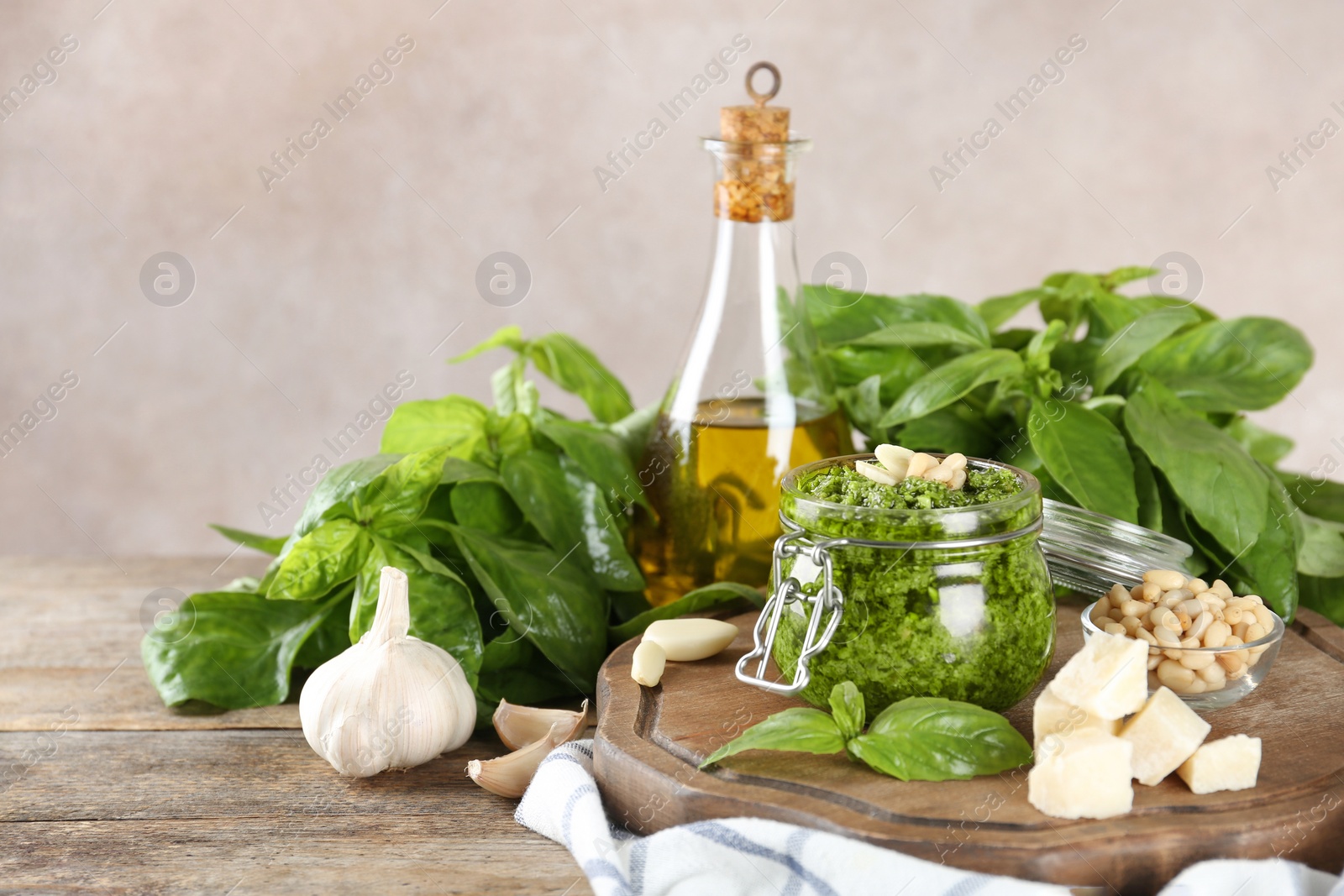 Photo of Composition with jar of pesto sauce and ingredients on table. Space for text