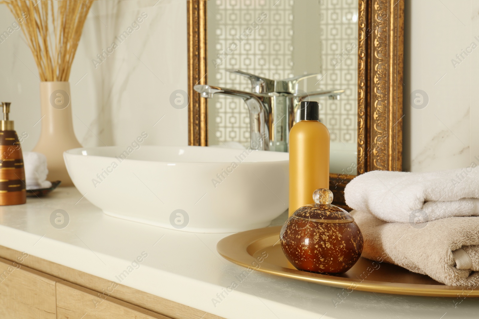 Photo of Toiletries and towels on white countertop near mirror in bathroom