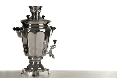 Traditional Russian samovar on wooden table against white background. Space for text