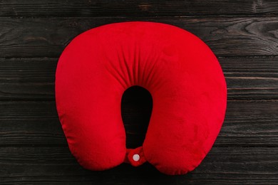 Red travel pillow on wooden background, top view