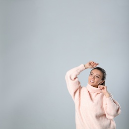 Photo of Young woman in stylish pink sweater on grey background, space for text