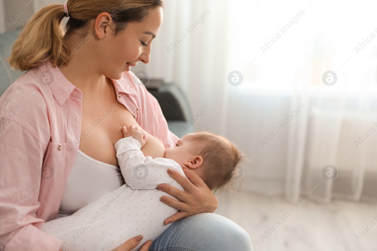 Photo of Young woman breastfeeding her baby at home