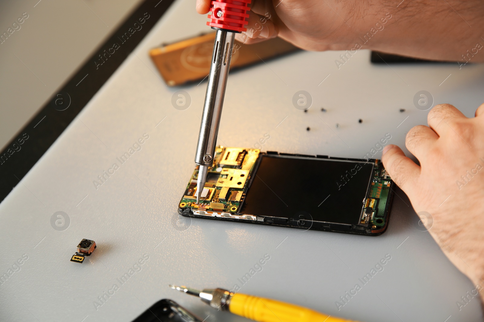 Photo of Technician repairing mobile phone at table, closeup