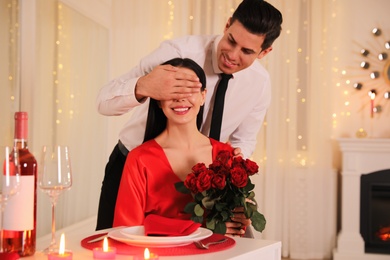 Man presenting roses to his beloved woman in restaurant. Romantic Valentine's day dinner