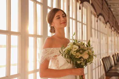 Photo of Gorgeous bride in beautiful wedding dress with bouquet in restaurant