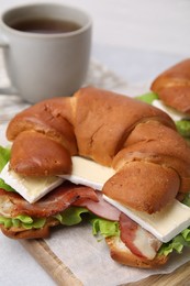 Tasty crescent roll with brie cheese, ham and bacon on table, closeup