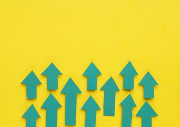 Photo of Paper arrows on yellow background, flat lay. Space for text