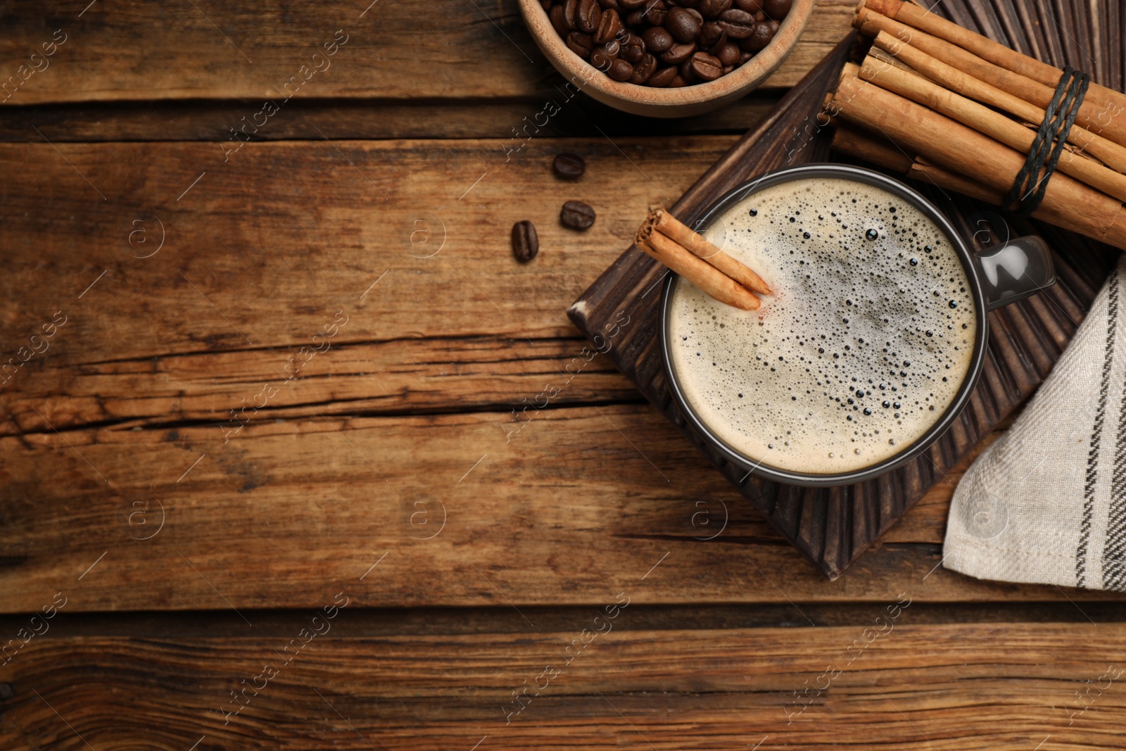 Photo of Cup of hot coffee with aromatic cinnamon on wooden table, flat lay. Space for text