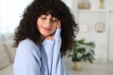 Young woman in stylish light blue sweater indoors, space for text