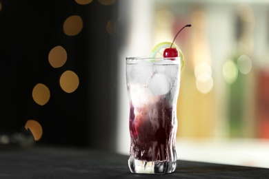 Photo of Fresh alcoholic cocktail with lemon and cherry on bar counter