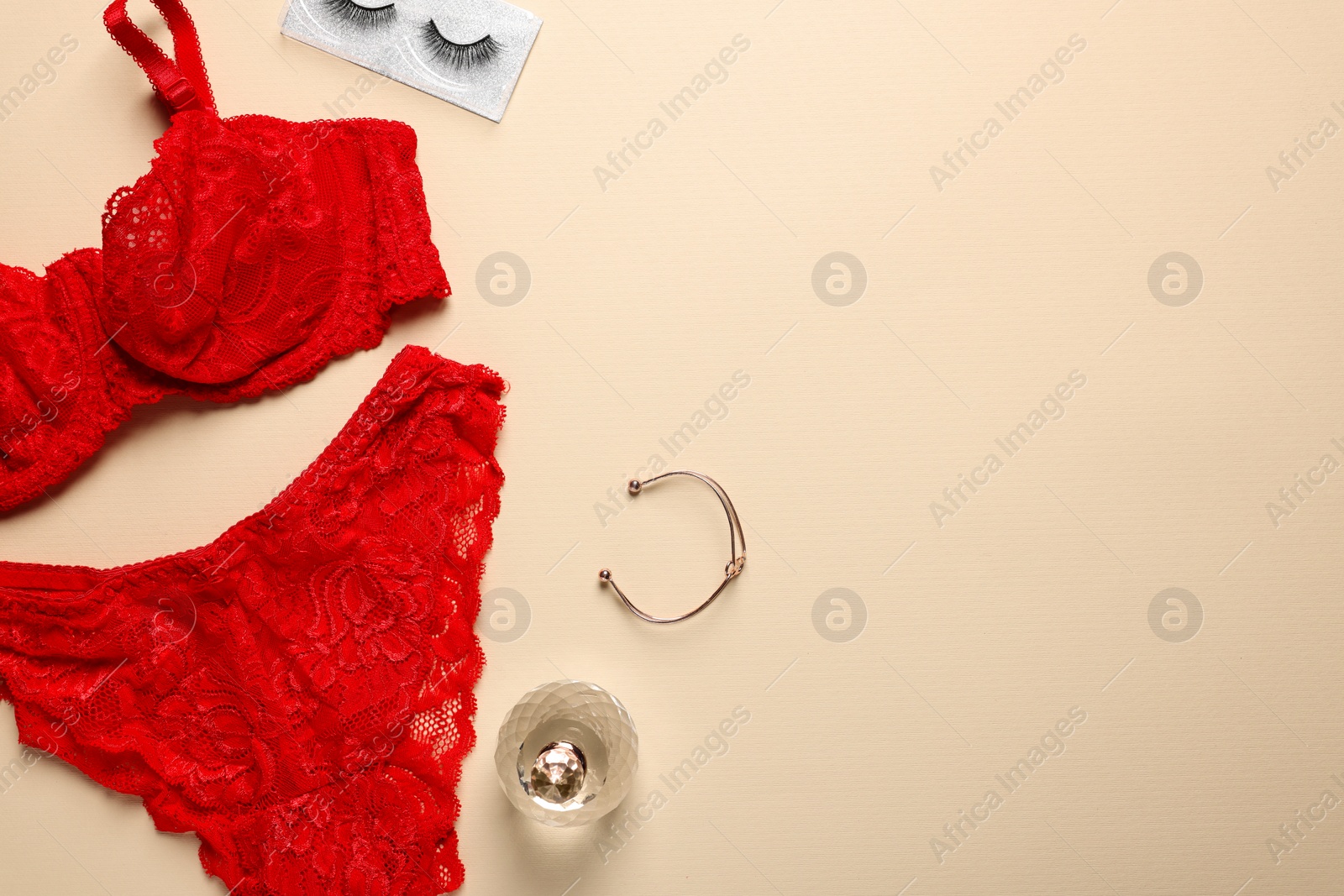 Photo of Elegant red women's underwear, bracelet and perfume on beige background, flat lay. Space for text